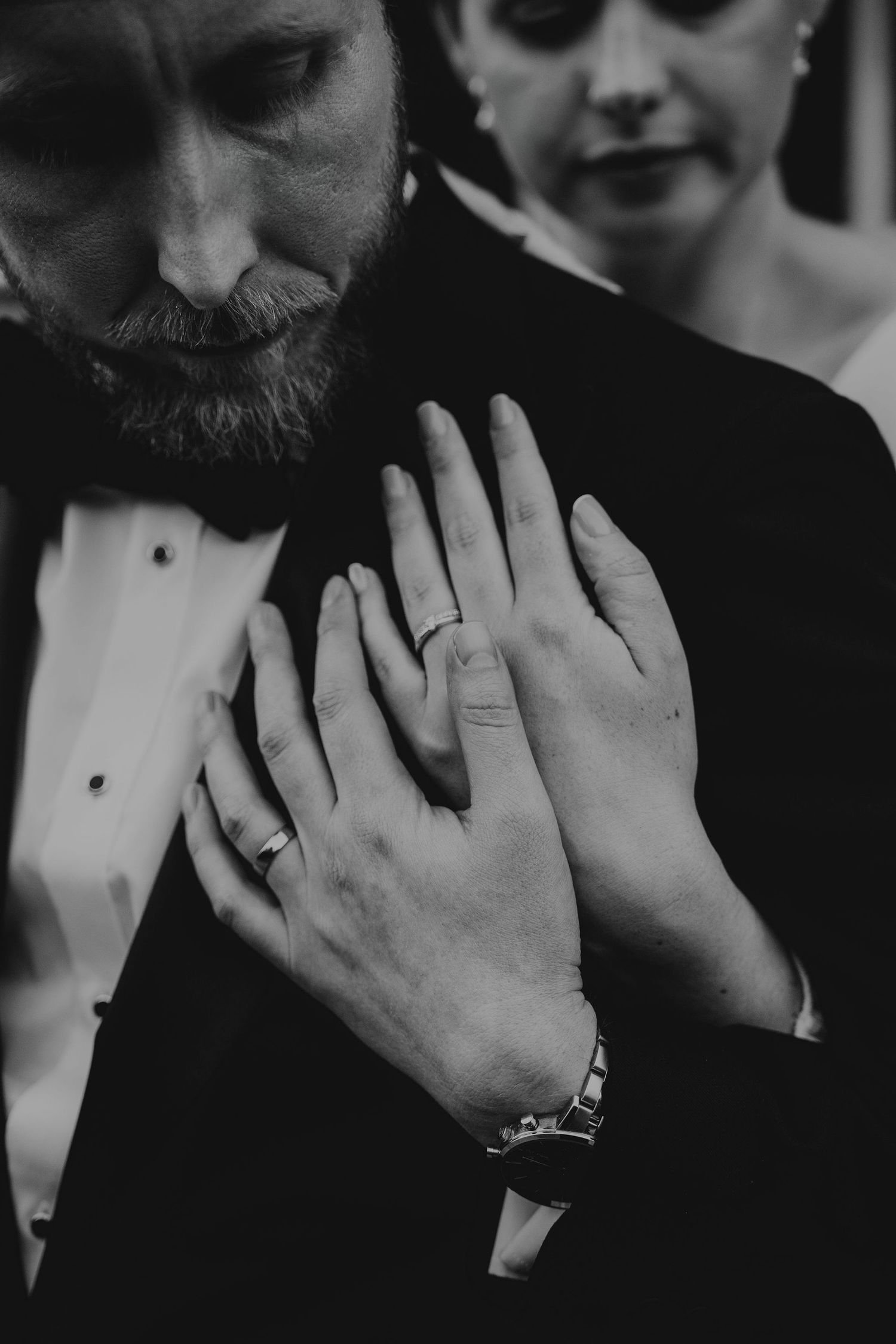 Black and white close-up photo of newlywed couple's hands showing their wedding rings.