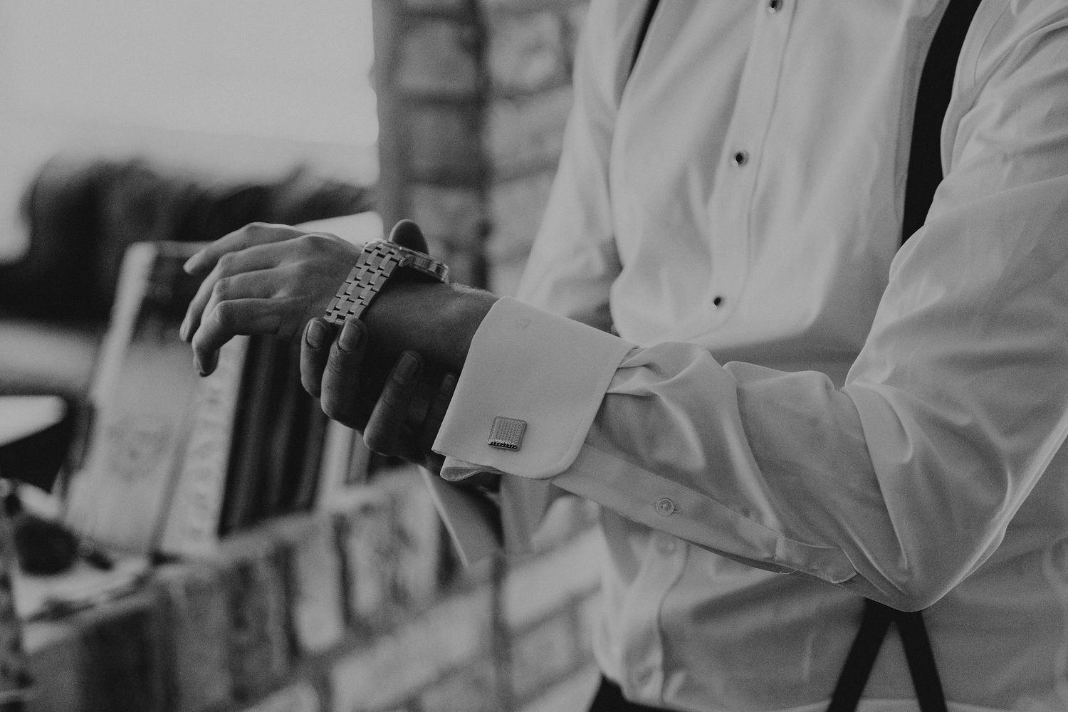 A close-up shot in black and white shows someone adjusting their dress shirt cuff and sleeve.