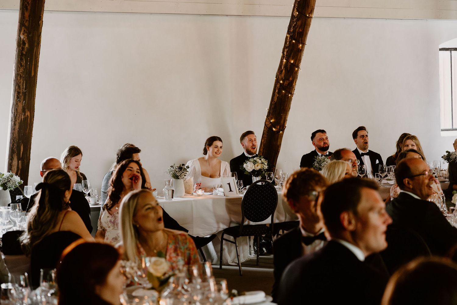 A crowded indoor event with people seated at tables listening attentively during what appears to be a professional gathering.
