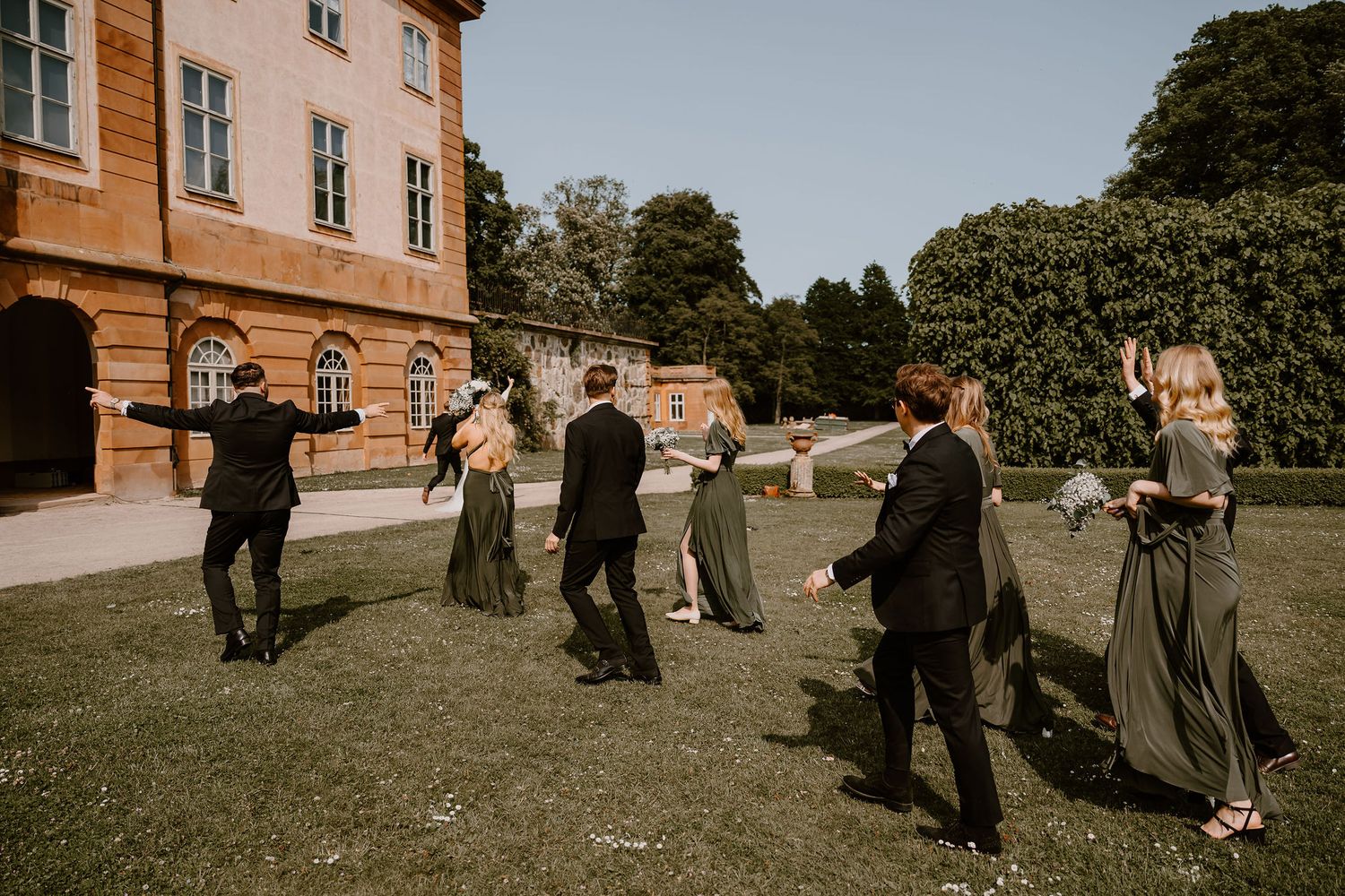 Well-dressed attendees mingle outside an elegant yellow building during an outdoor social gathering.