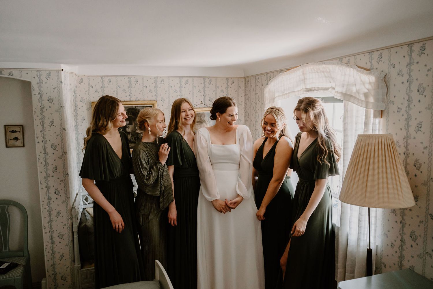 Various candid wedding preparation scenes show bridesmaids and gowns against floral wallpaper in a bright room.