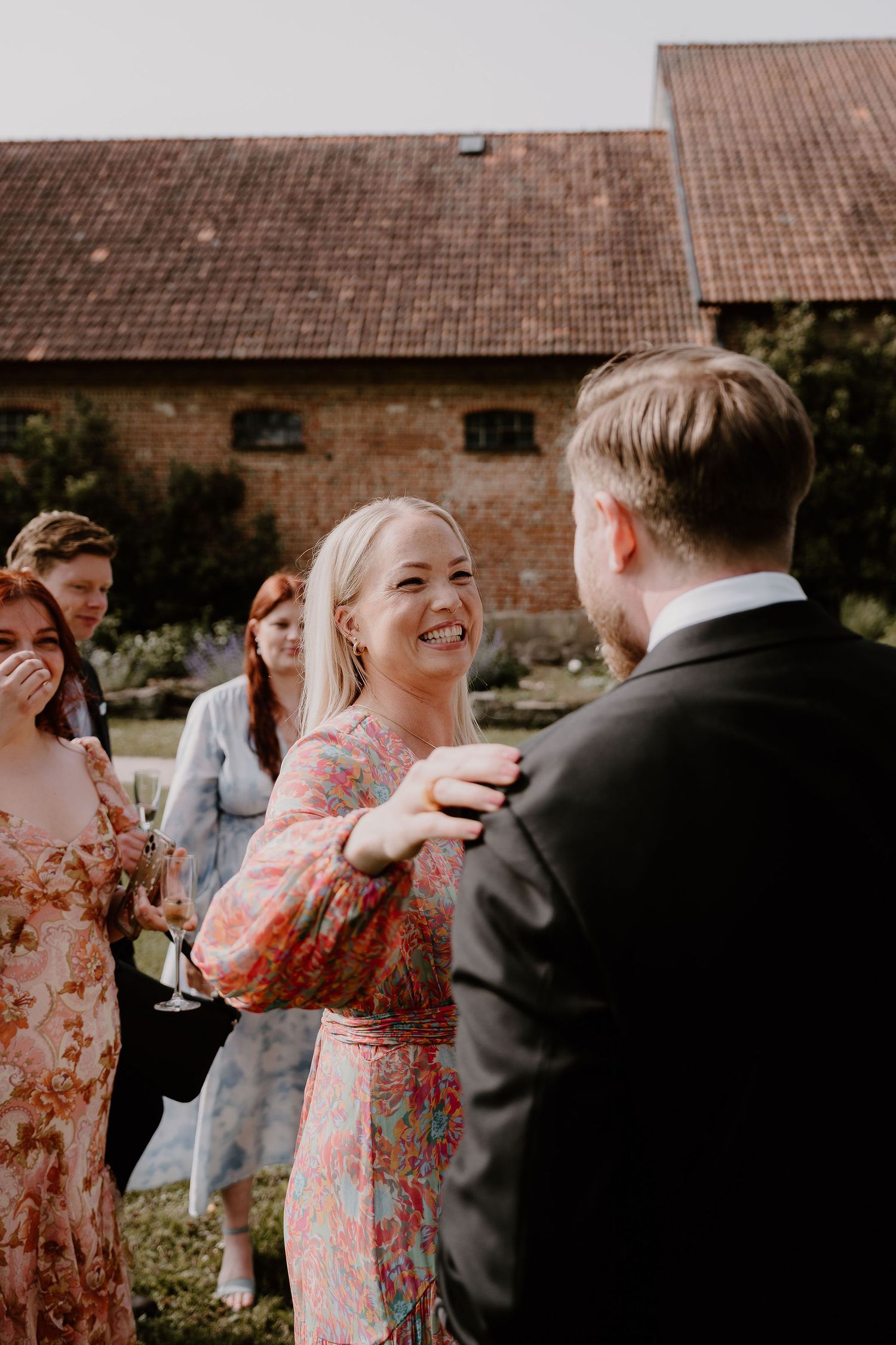 Candid sequence of a couple sharing an intimate moment at an outdoor celebration beside brick buildings.