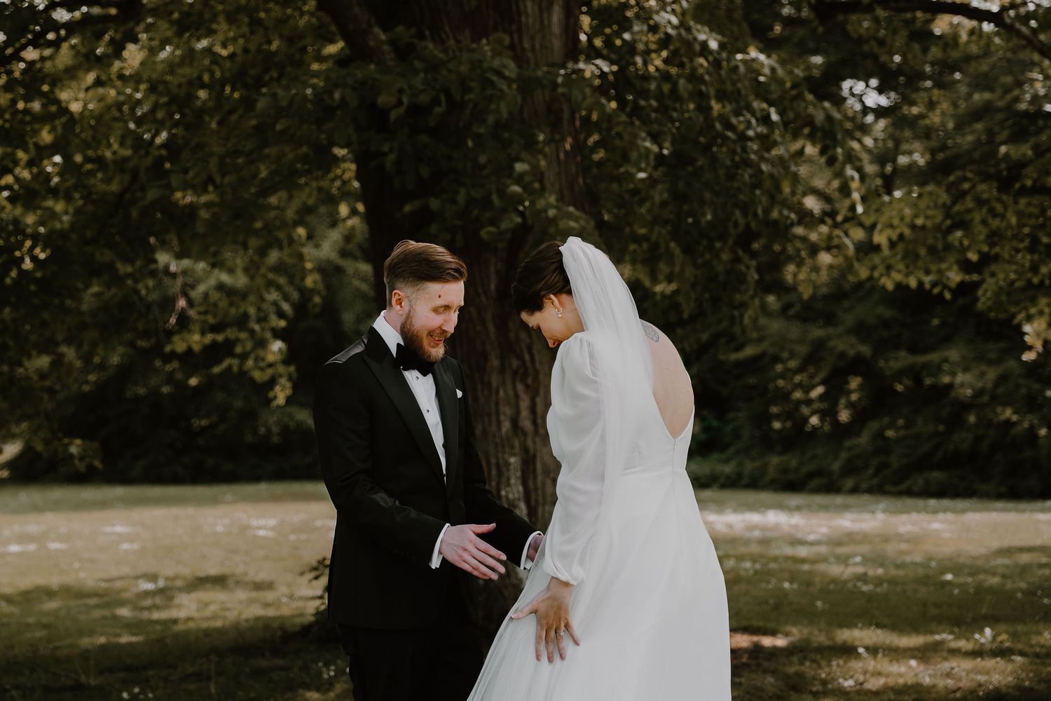 A couple shares an intimate moment during their outdoor wedding, surrounded by trees and greenery.