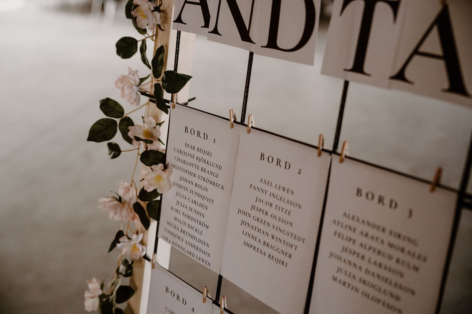 A minimalist wedding seating chart display with modern typography and white cards against a dark background.