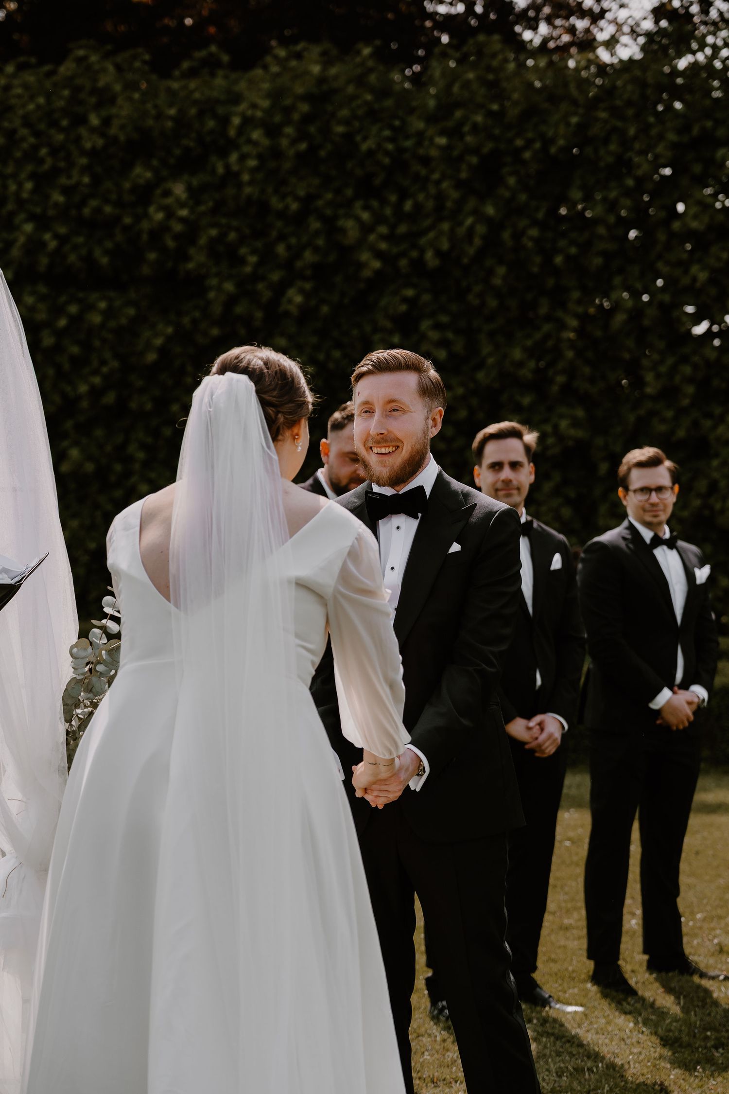 A wedding ceremony captured during an outdoor celebration with the wedding party standing on a lawn.