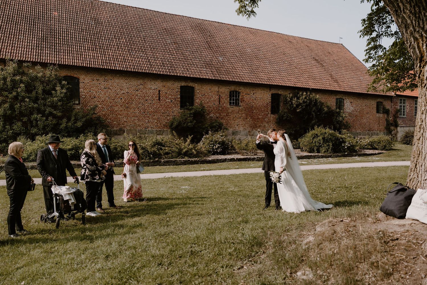 Rustic barn wedding ceremony taking place outdoors with bridal party on a sunny day.