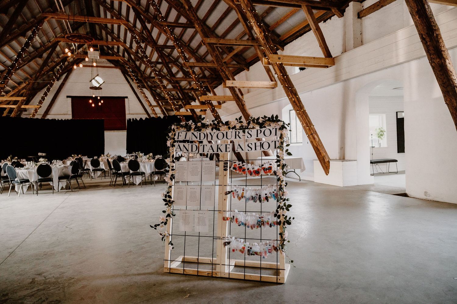 Panoramic view of rustic barn wedding venue with exposed wooden beams and white decor in a spacious loft setting.