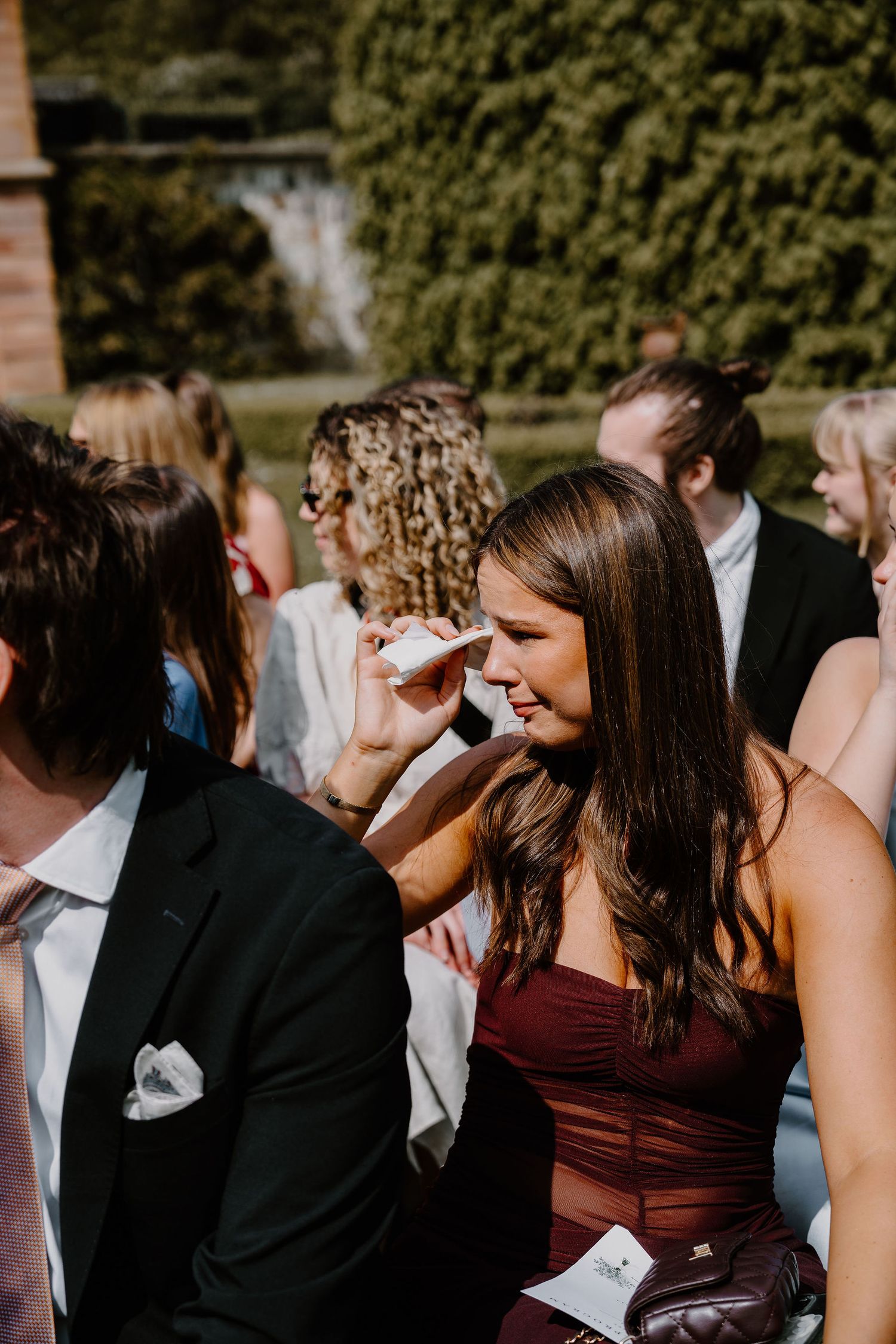 Wedding guests enjoy themselves during an outdoor reception celebration with lush greenery in the background.
