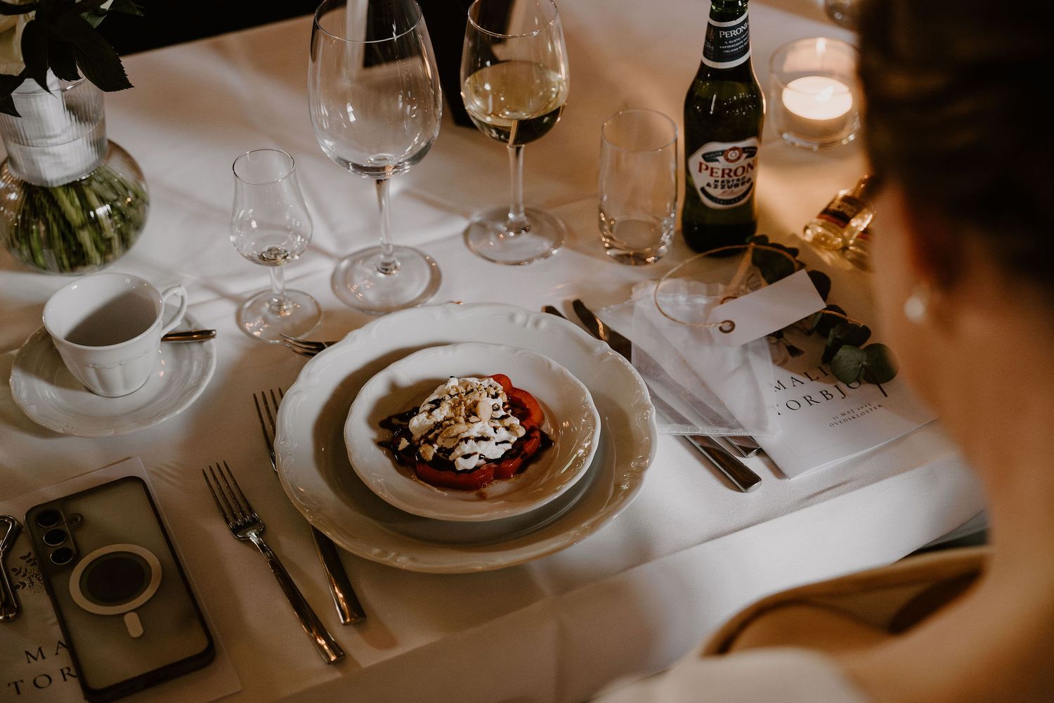 Elegant table setting at upscale restaurant with wine glasses, white tablecloth, and candlelight creating romantic ambiance.