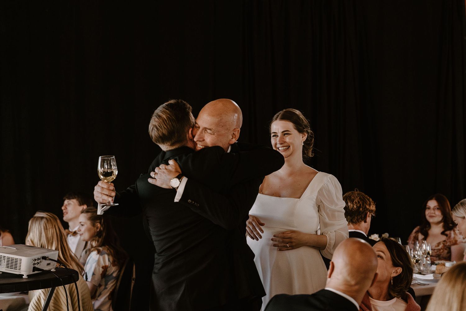 Wedding guests dance and celebrate together during an elegant evening reception on a black background.