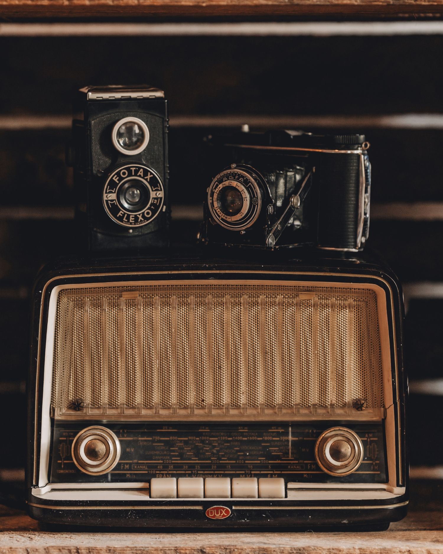 Vintageinspirerad hylla med gammal radio och analoga kameror i varma trätoner.