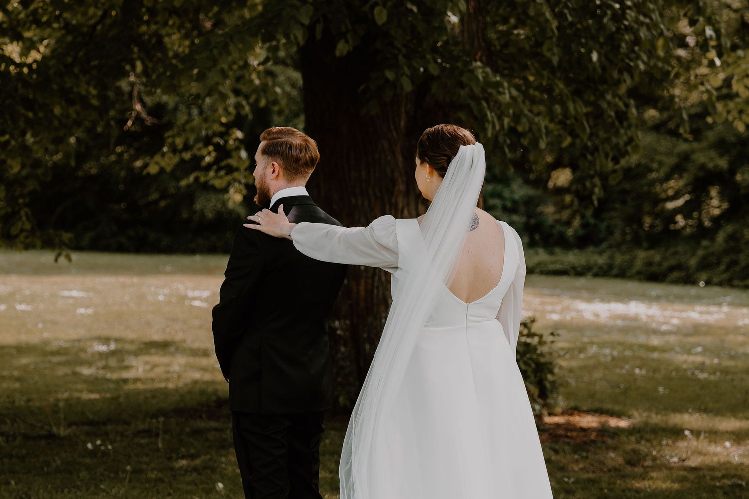Bride and groom walking together in a garden setting on their wedding day during golden sunlight.