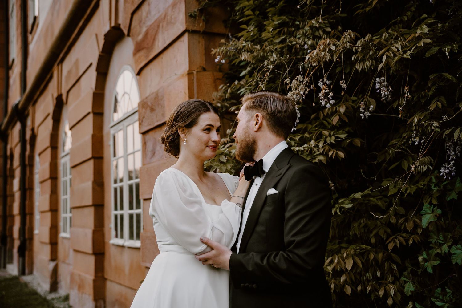 Two newlyweds share an intimate moment together during their autumn wedding in a rustic brick courtyard.