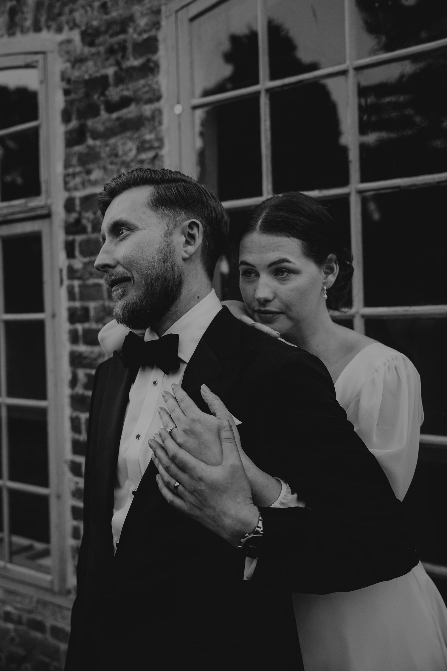 Black and white photo of a romantic outdoor moment during a wedding between partners in formal attire.