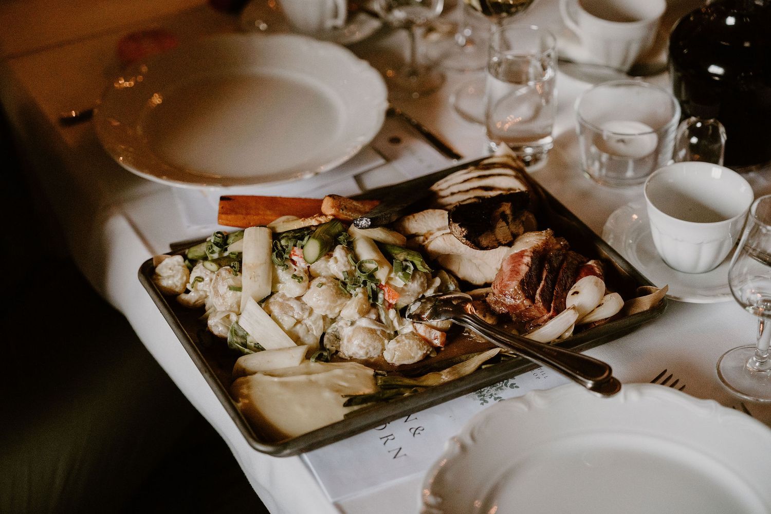 Elegant table setting with plated appetizers served on a silver tray with white plates and wine glasses.