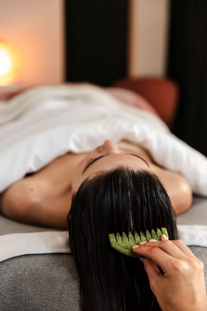 Person receiving relaxing spa treatment with green jade comb in hair.