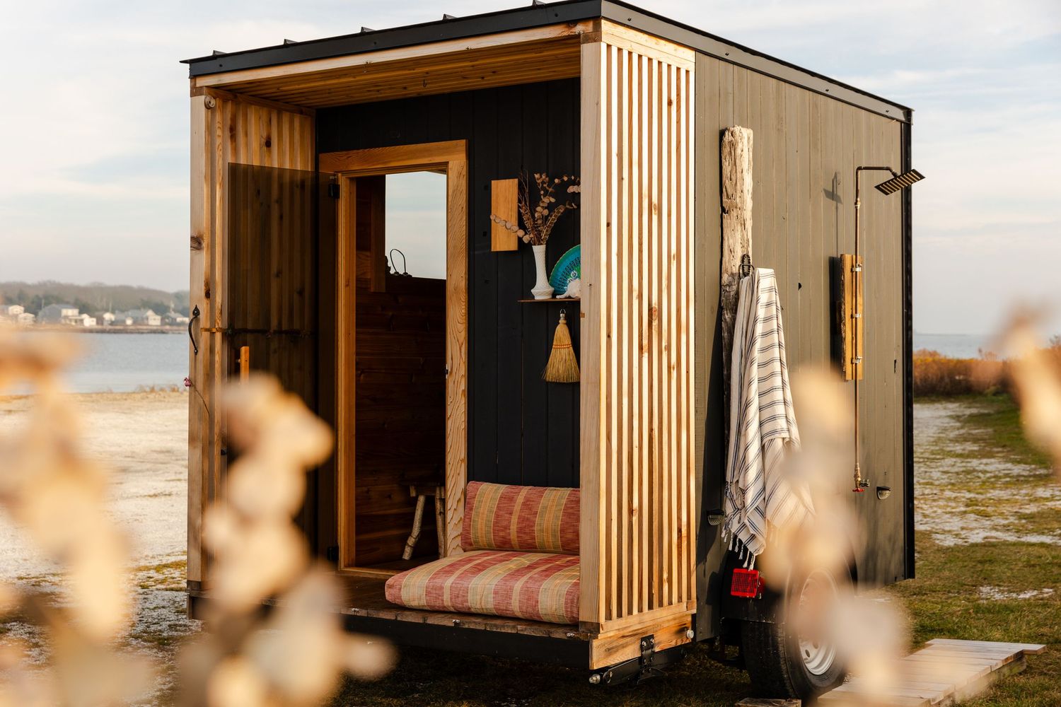 Modern wooden shipping container converted into a cozy tiny home set against a serene natural landscape.
