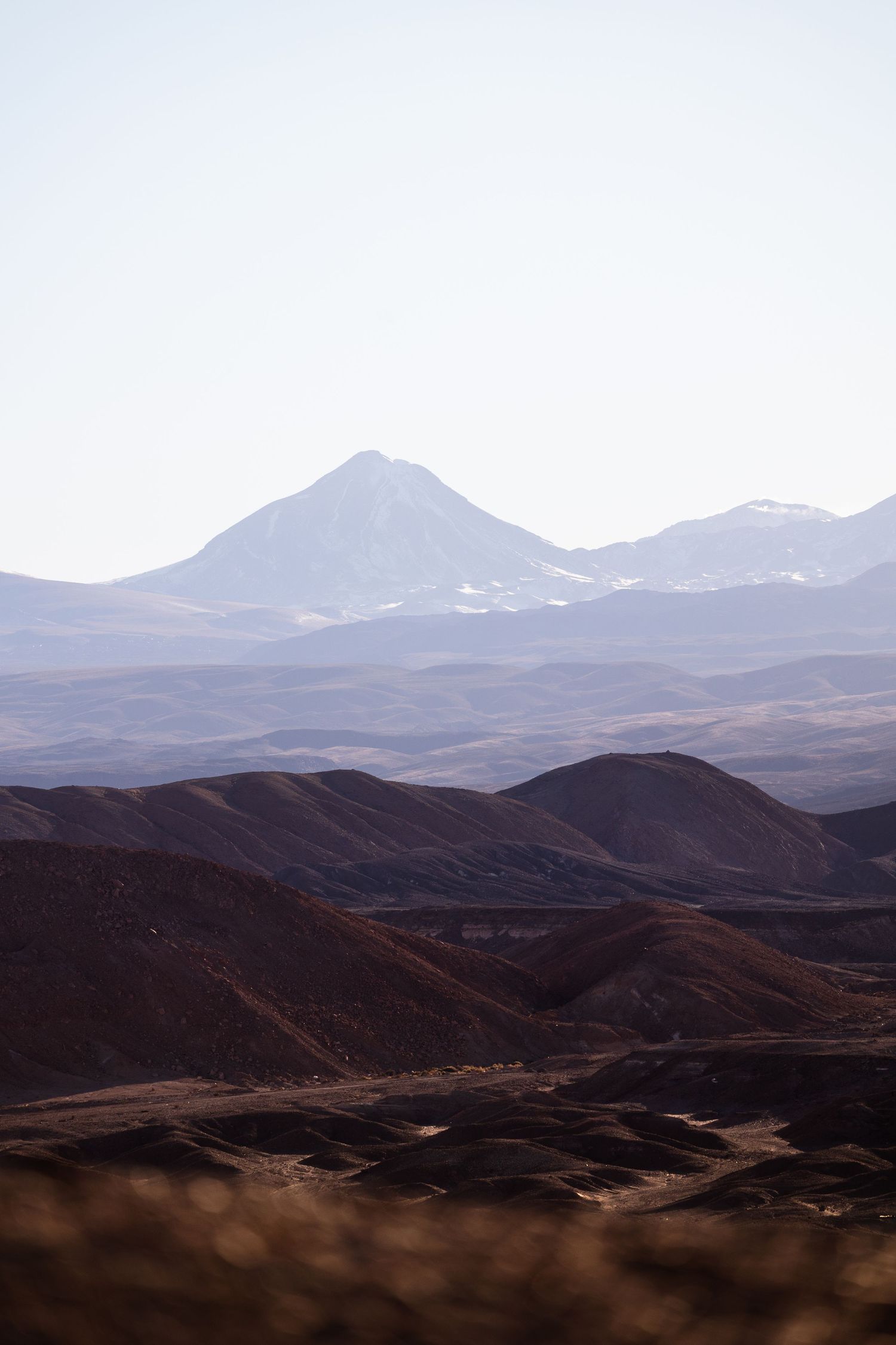 Panoramic mountain landscape with rugged brown hills stretching into the distance under a muted sky.