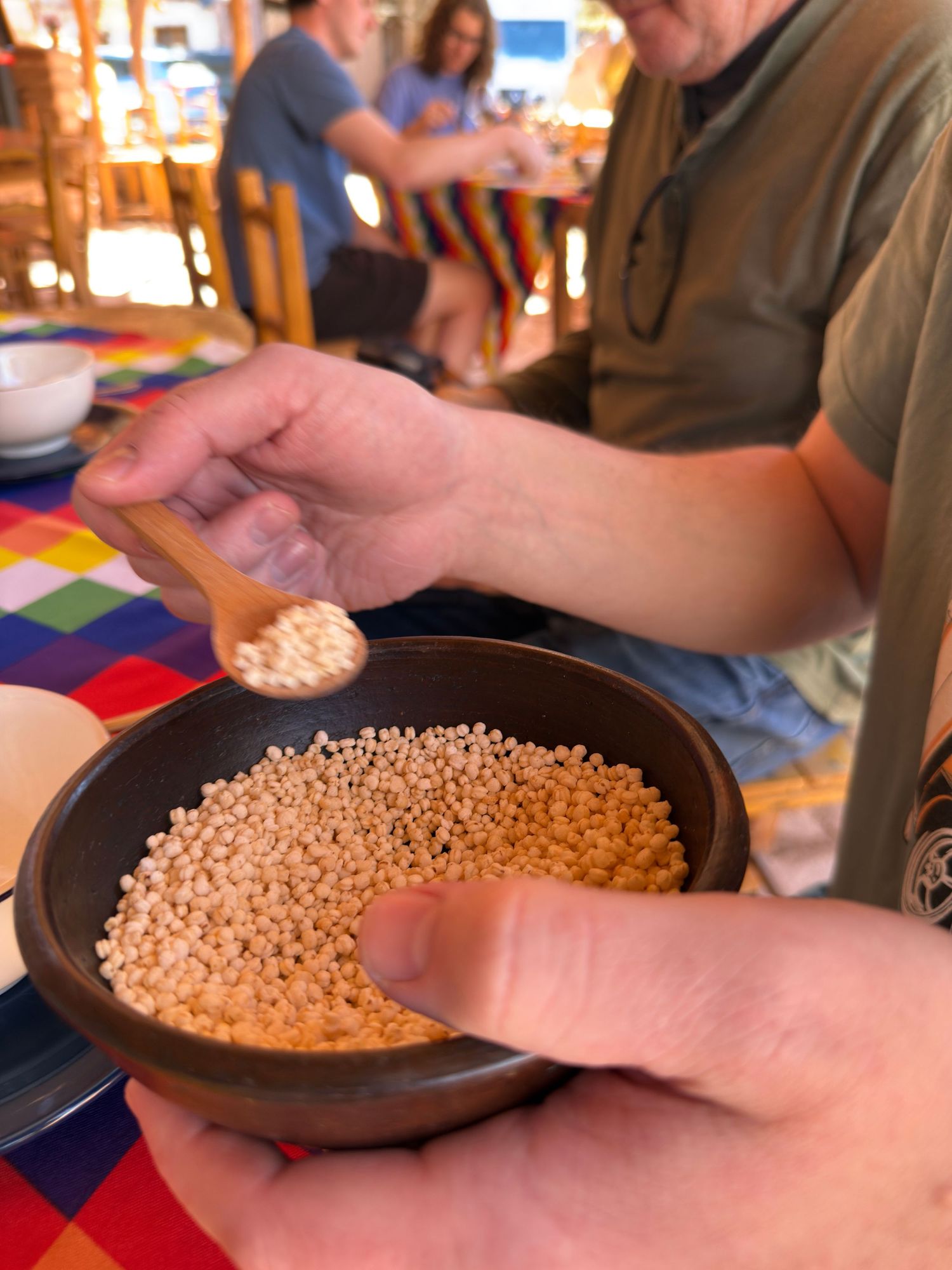 A wooden bowl filled with soybeans being poured and handled across multiple frames in sequence.
