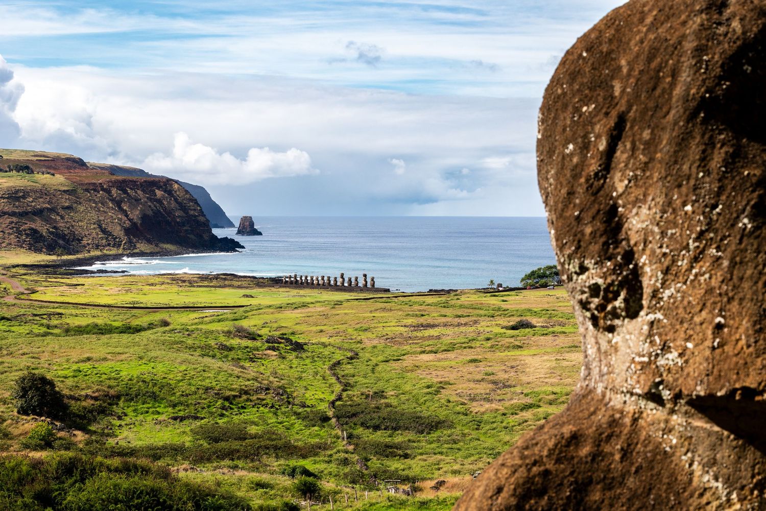 Aerial panoramic view of Easter Island's rugged coastline showing dramatic cliffs and green grasslands meeting the ocean.