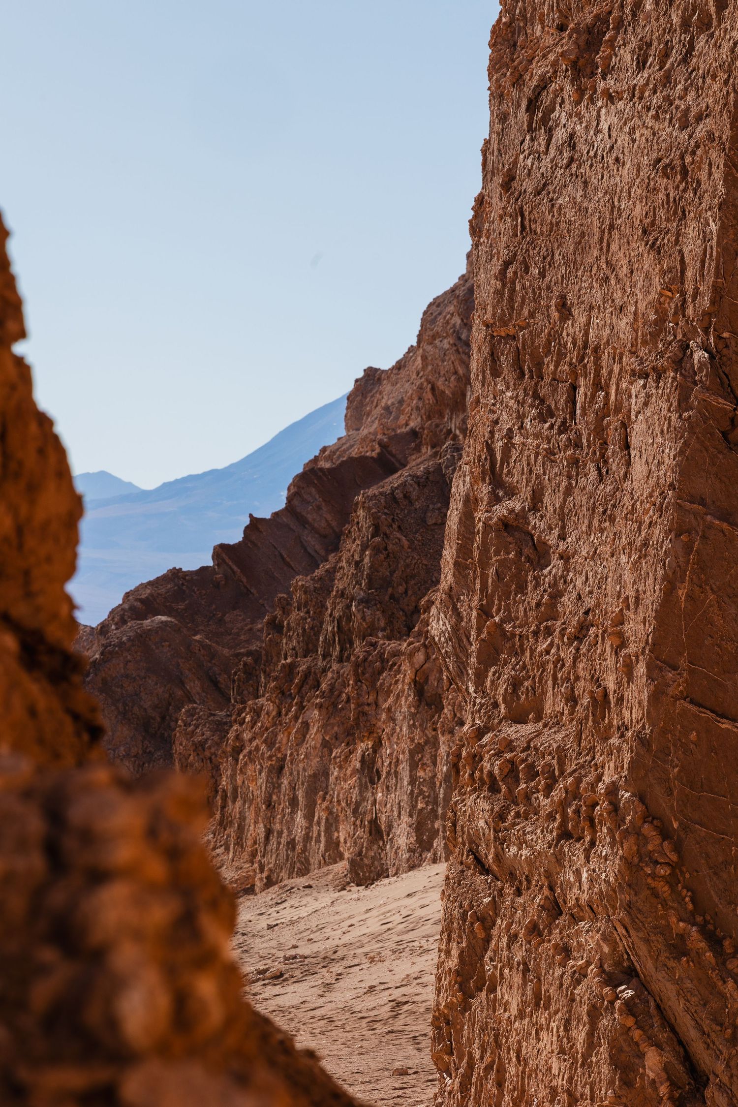 Rugged desert canyon walls rise against a bright sky in Death Valley's stark landscape.