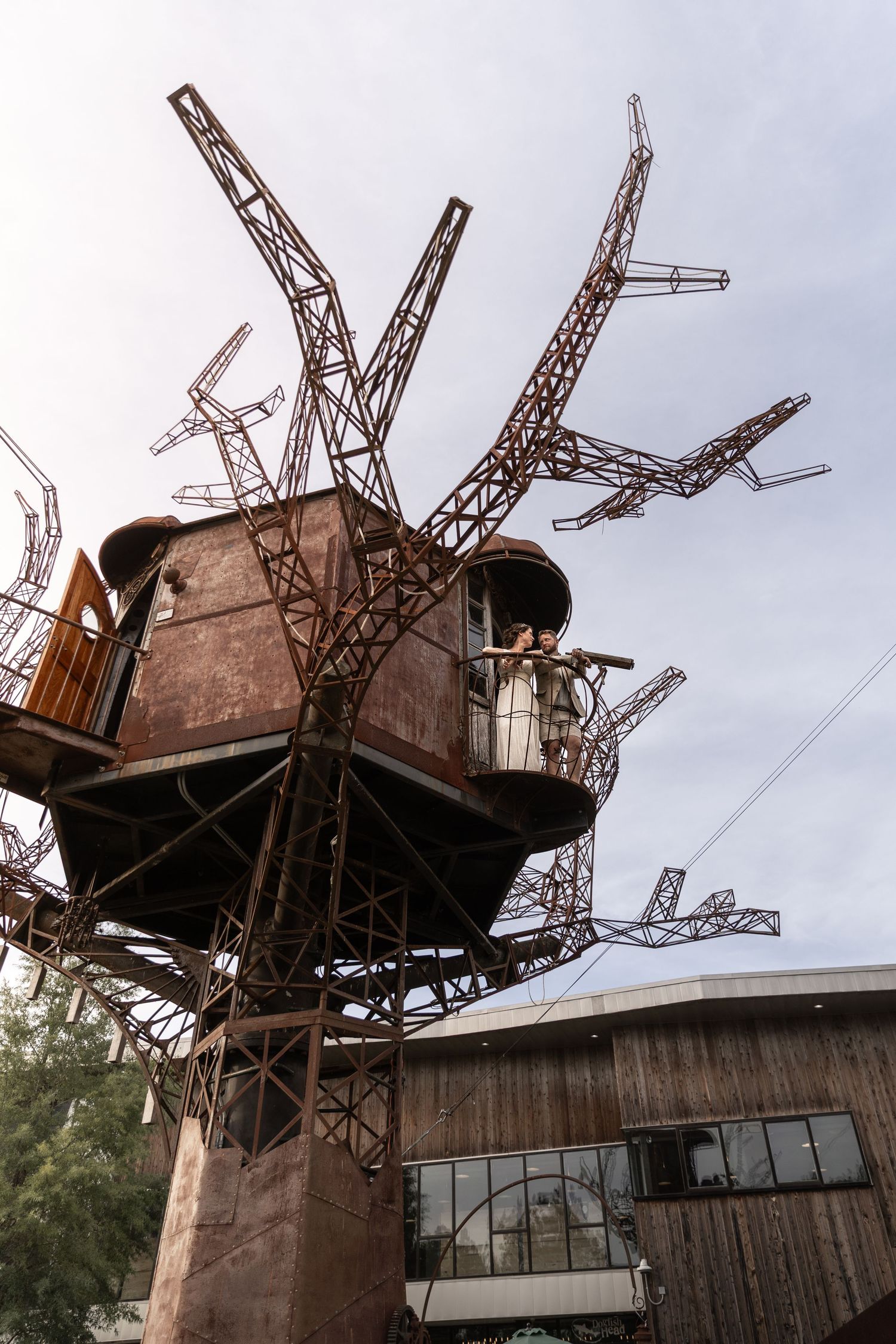 Unique treehouse structure made of metal latticework and industrial materials mounted on a concrete pillar.