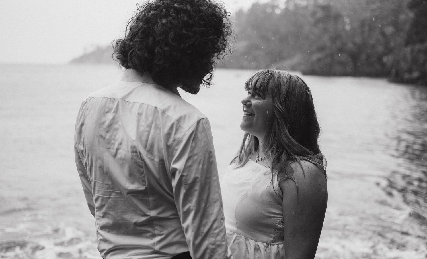 Black and white romantic portrait of couple by waterside in vintage style.
