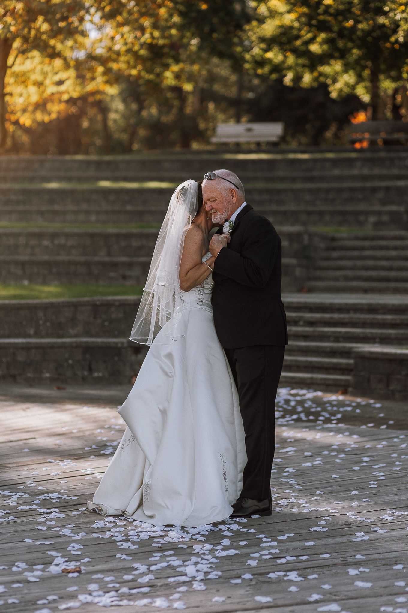 Romantic wedding moment on stone steps during golden hour with scattered petals.