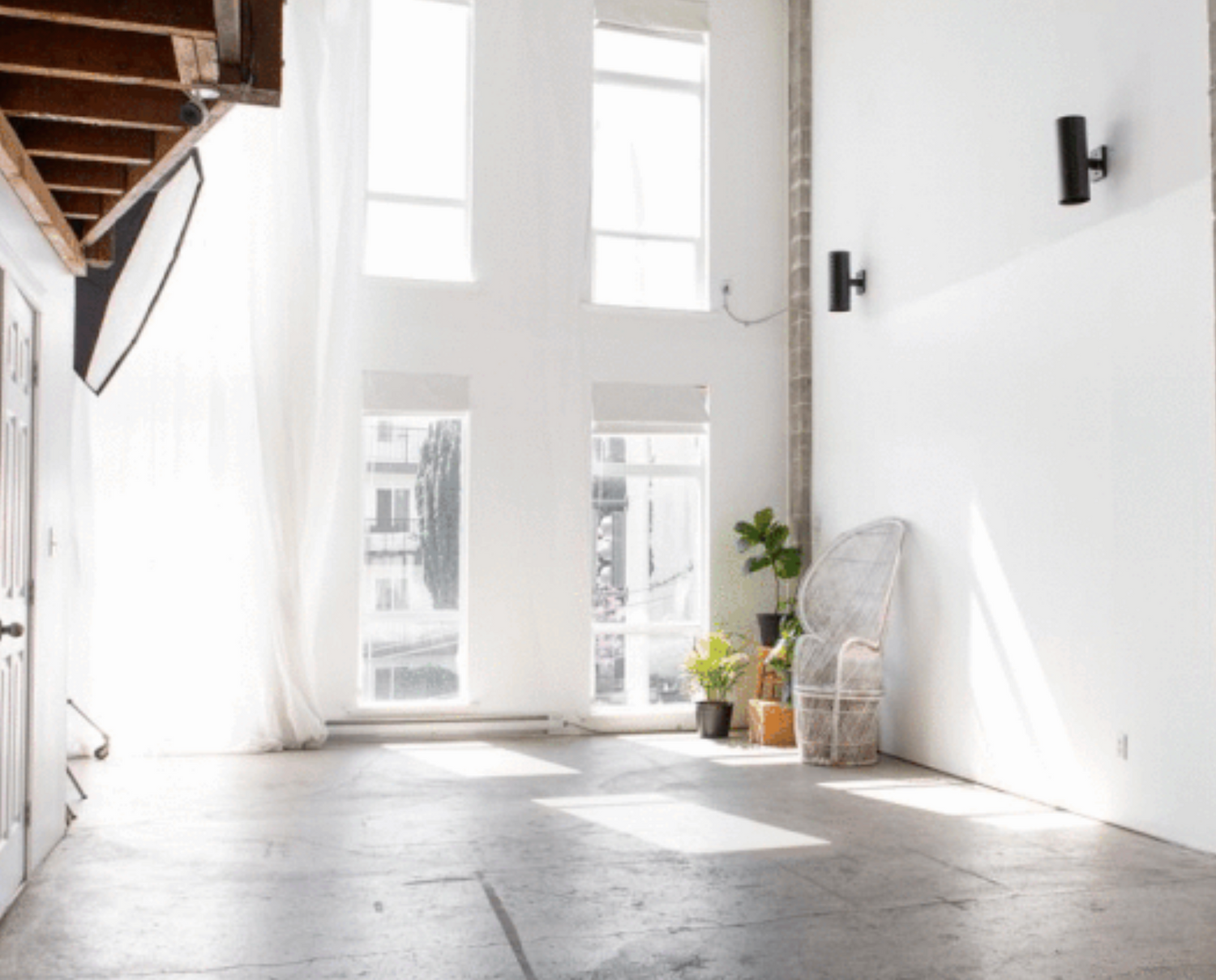 Bright minimal space with tall windows, white walls and exposed wooden beams.