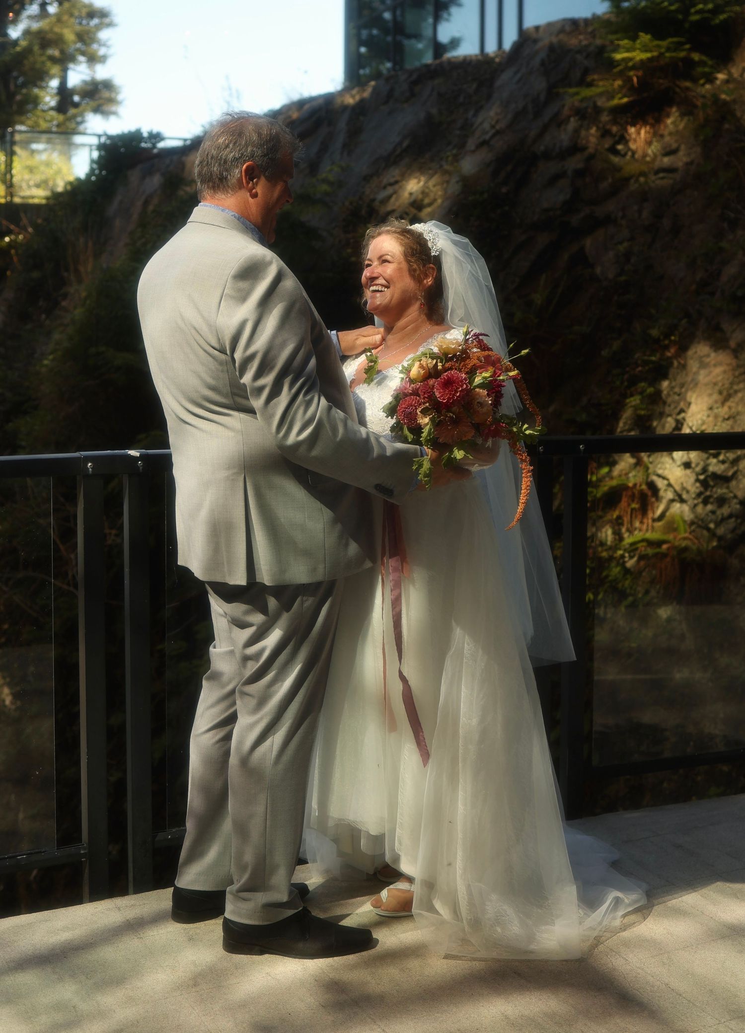 A couple shares a joyful moment during their outdoor wedding ceremony against a rocky backdrop.