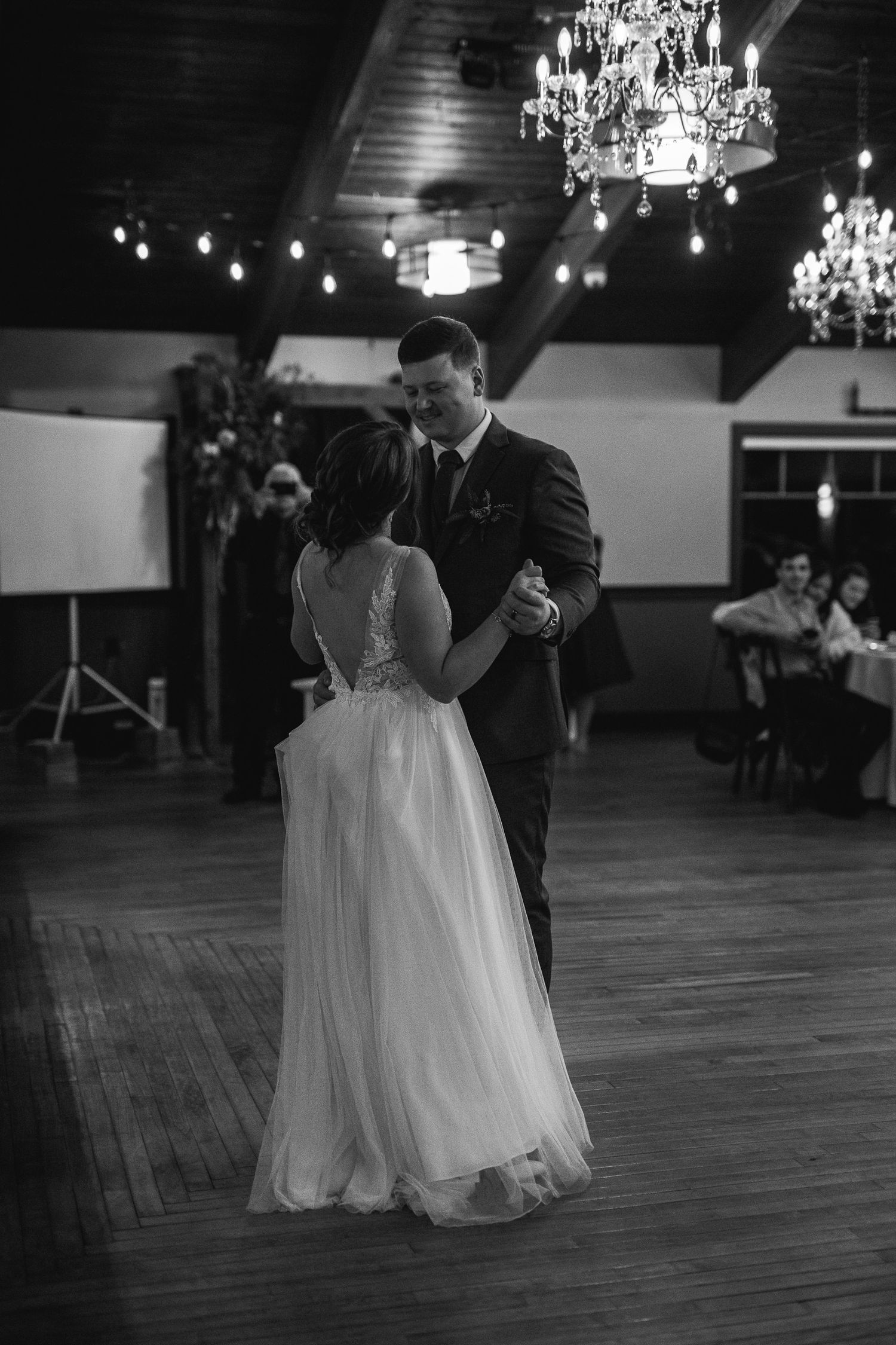 A romantic first dance moment under crystal chandeliers in a classic ballroom setting.