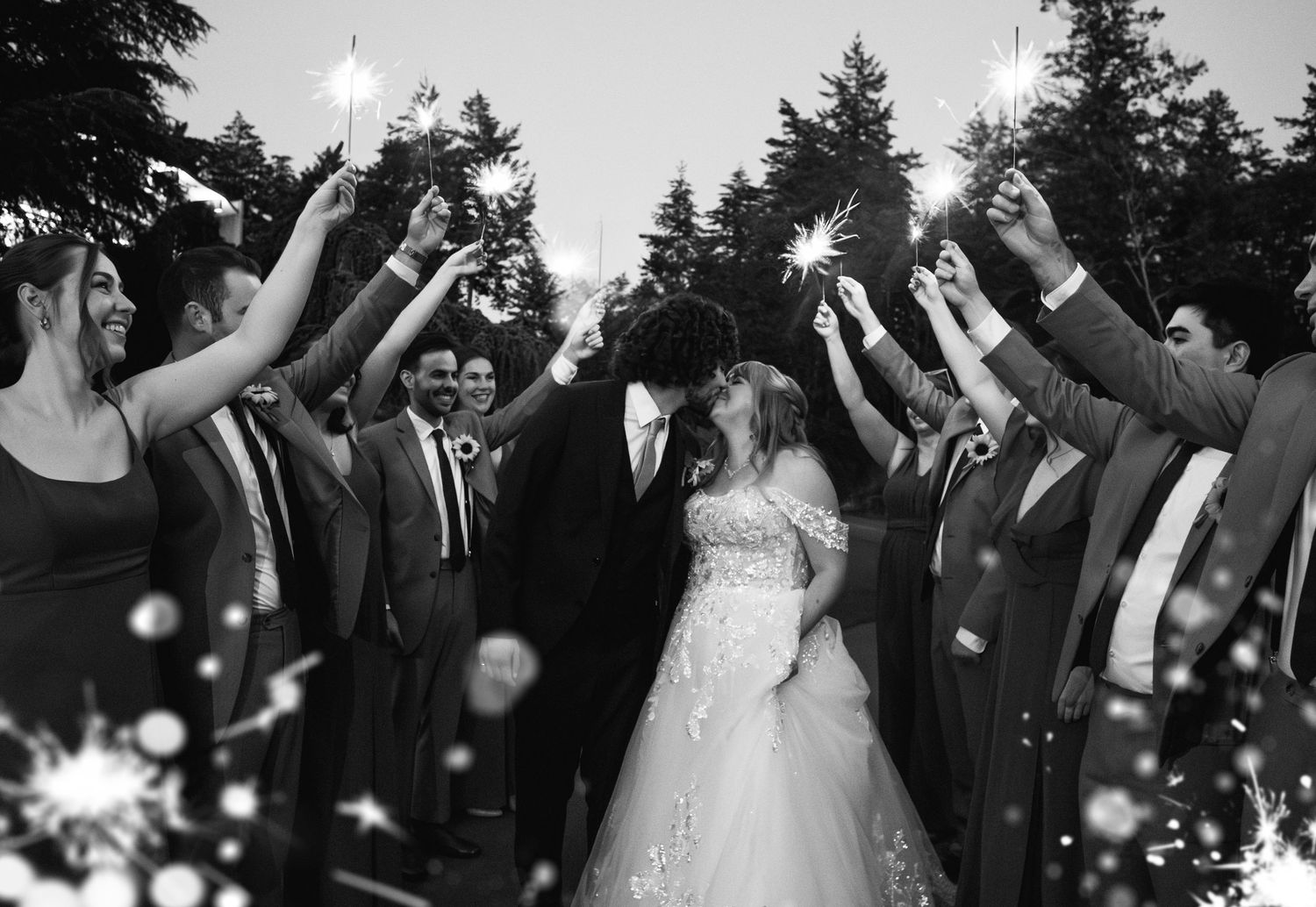 A wedding celebration moment captured in black and white with sparklers creating a magical archway effect.
