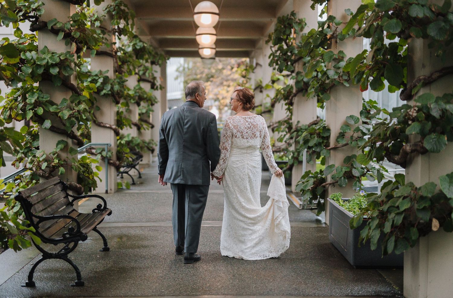 A couple walks down a vine-covered walkway during their wedding celebration.