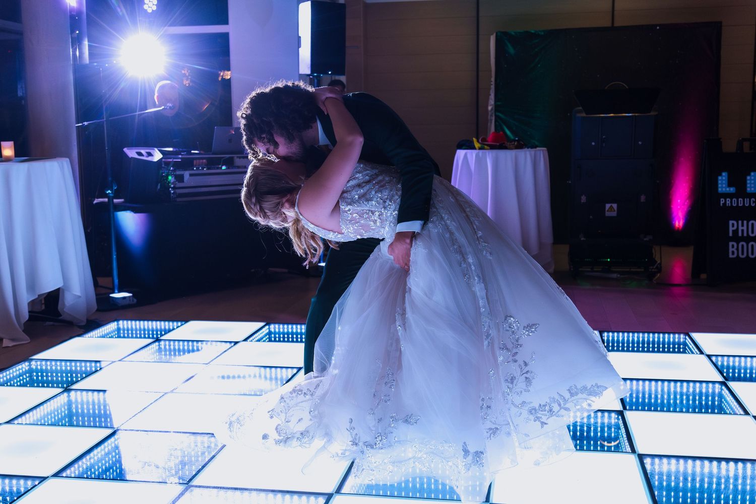 Romantic dip dance on an illuminated checkerboard dance floor at a wedding reception.