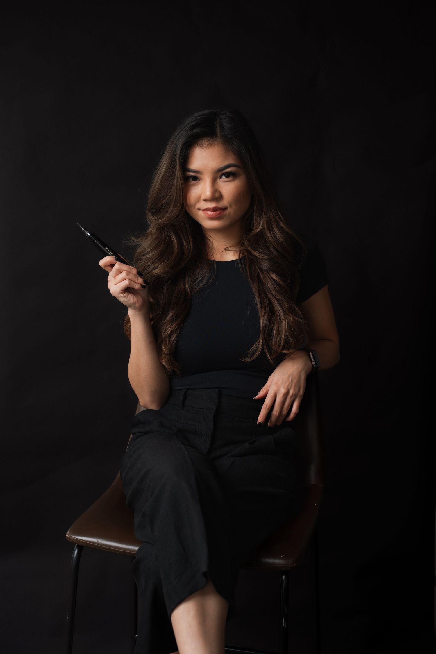 Portrait against a dark background showing elegant black attire and professional styling.