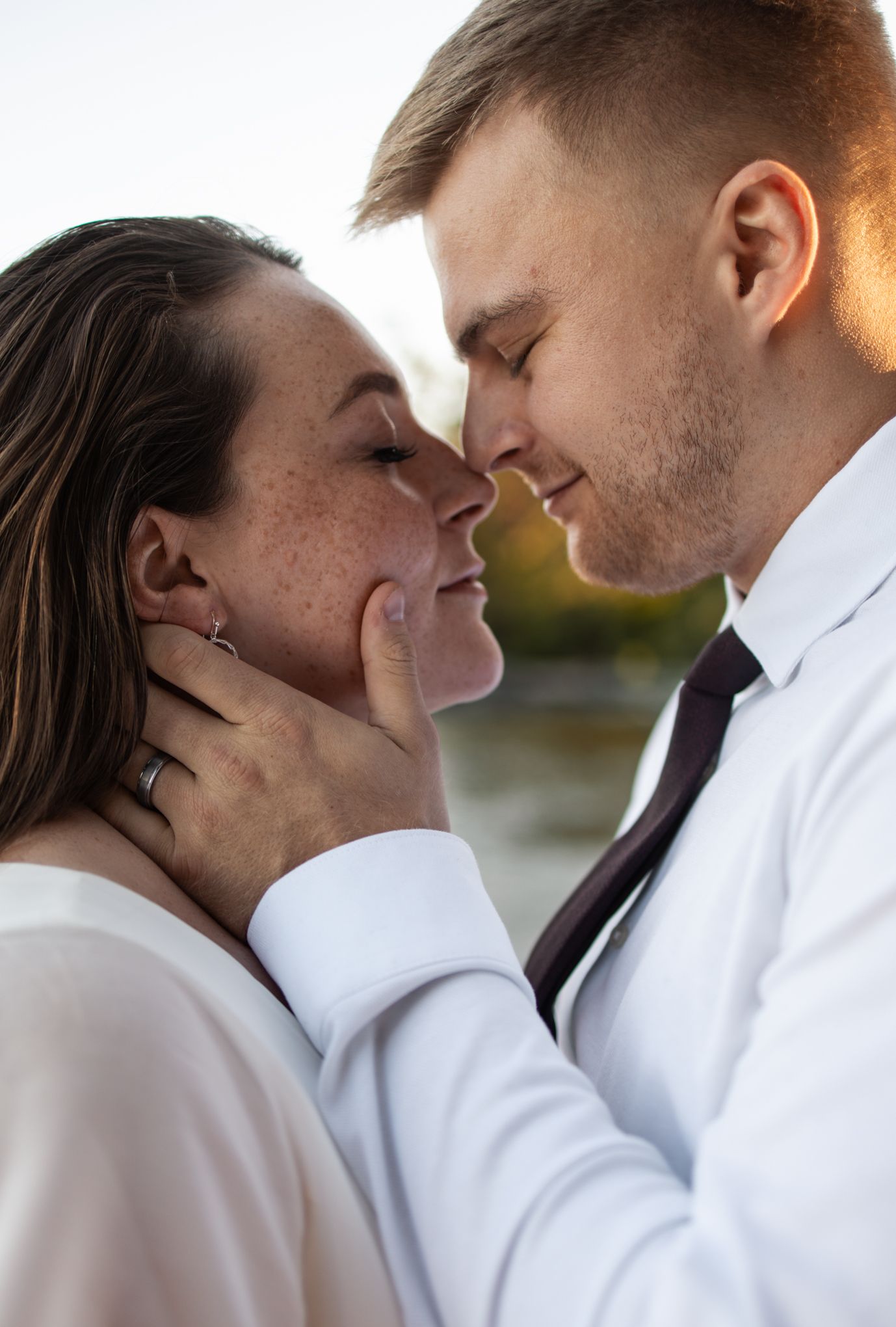 Intimate close-up of a couple sharing a tender moment in warm sunset lighting.