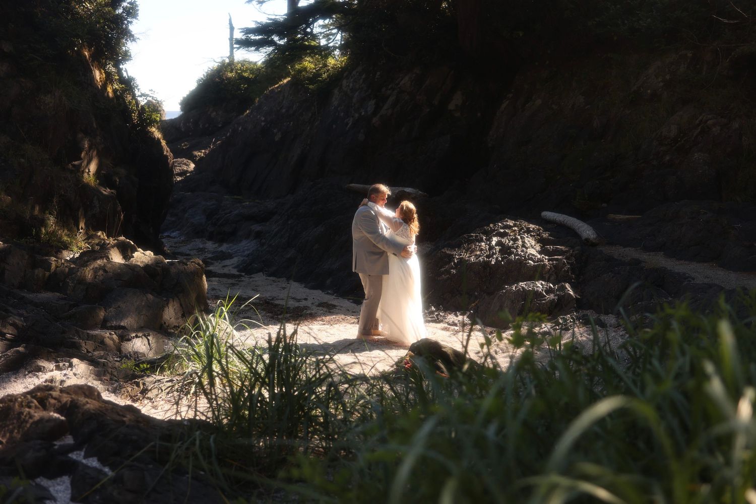 Newlyweds embrace in a dramatic rocky canyon setting during their wedding photoshoot.