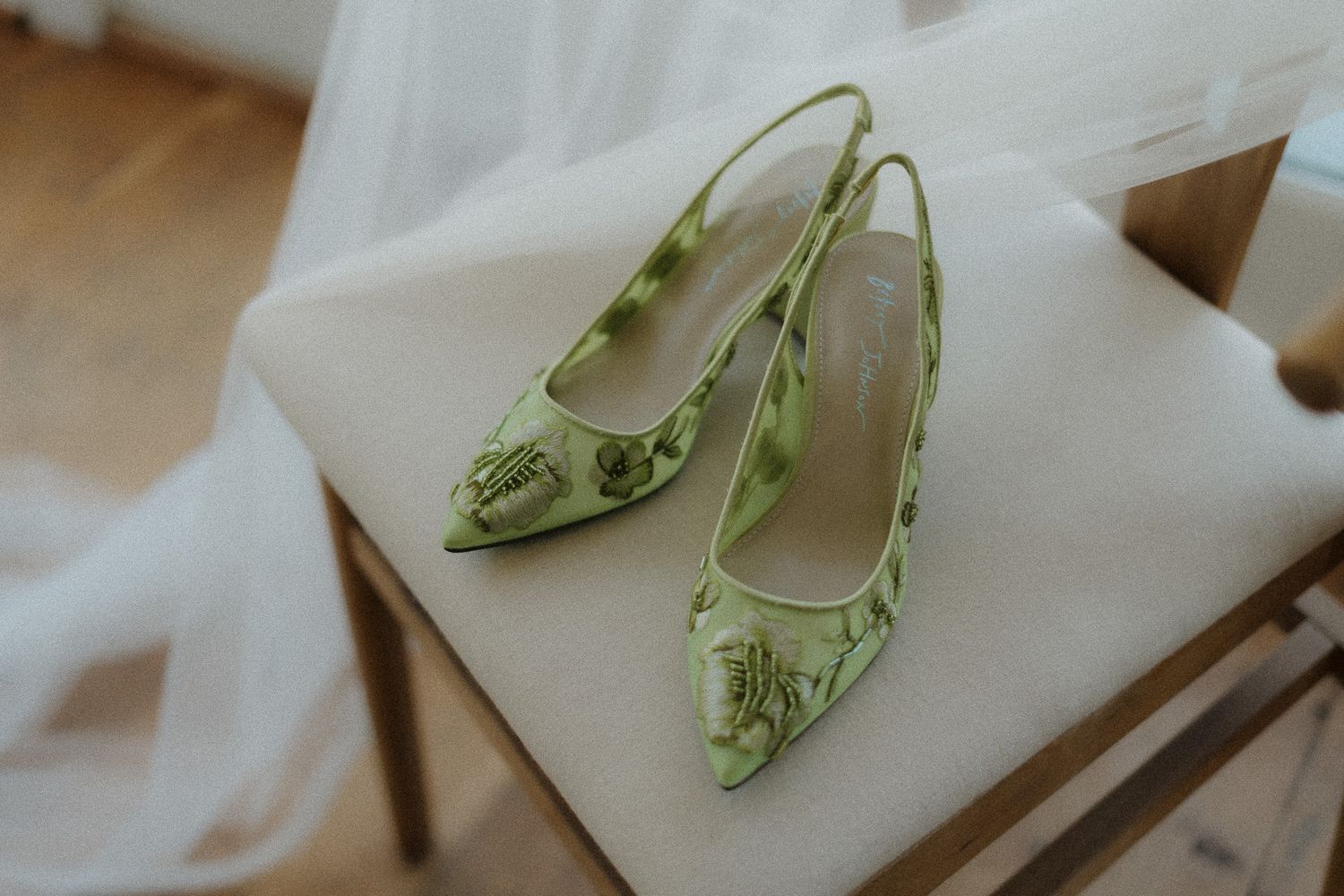 Elegant mint green lace kitten heel bridal shoes displayed on white fabric.