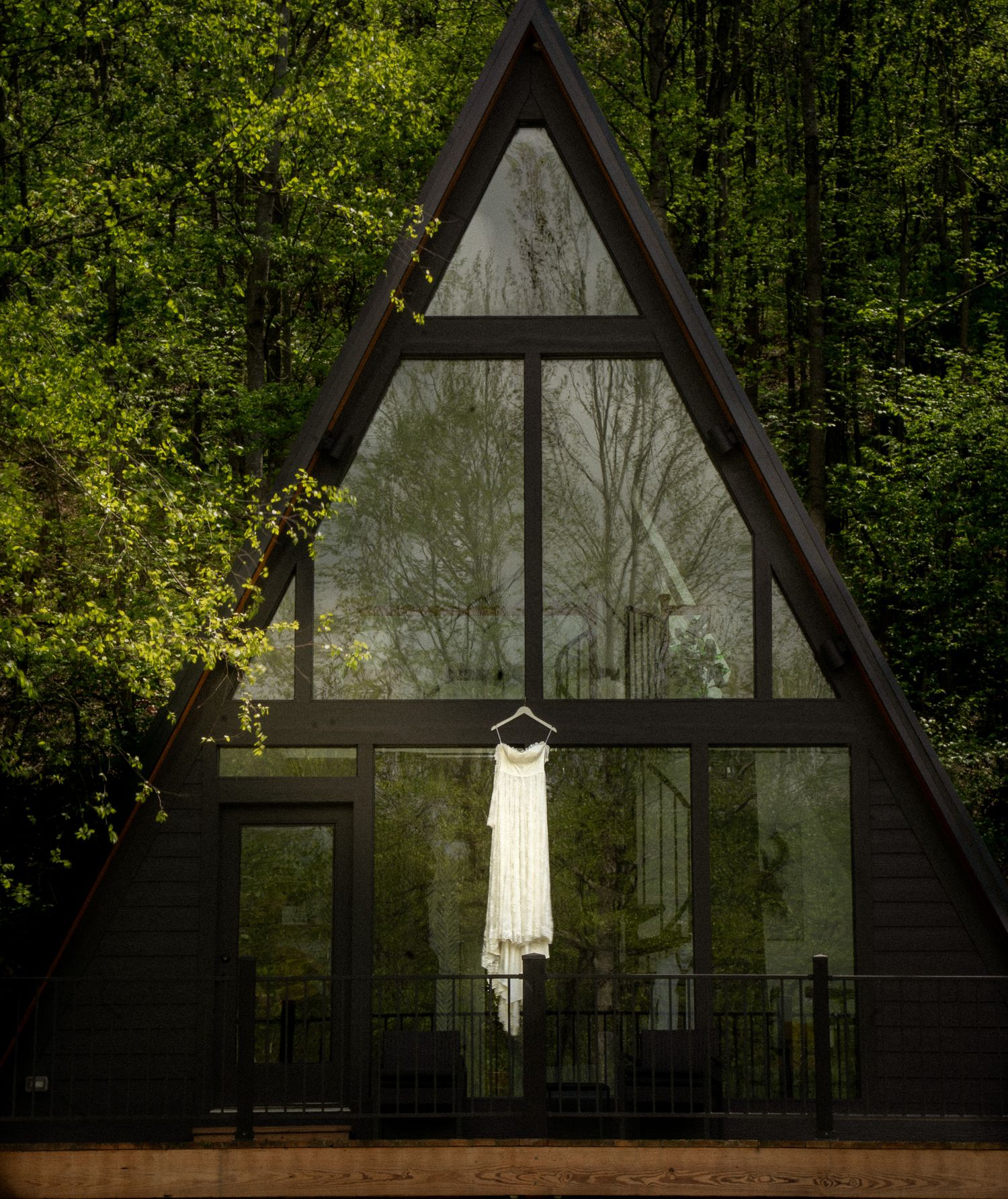 Bridal gown hanging in front of a modern A-frame cabin, surrounded by forest—perfect setting for a destination elopement in nature.