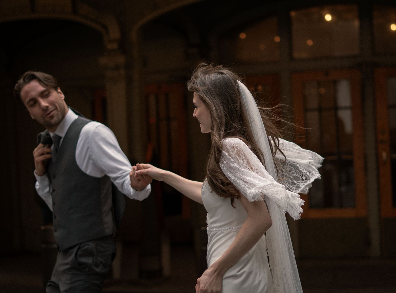 A couple sharing a joyful moment on their wedding day, with the bride in a flowing white dress and veil.
