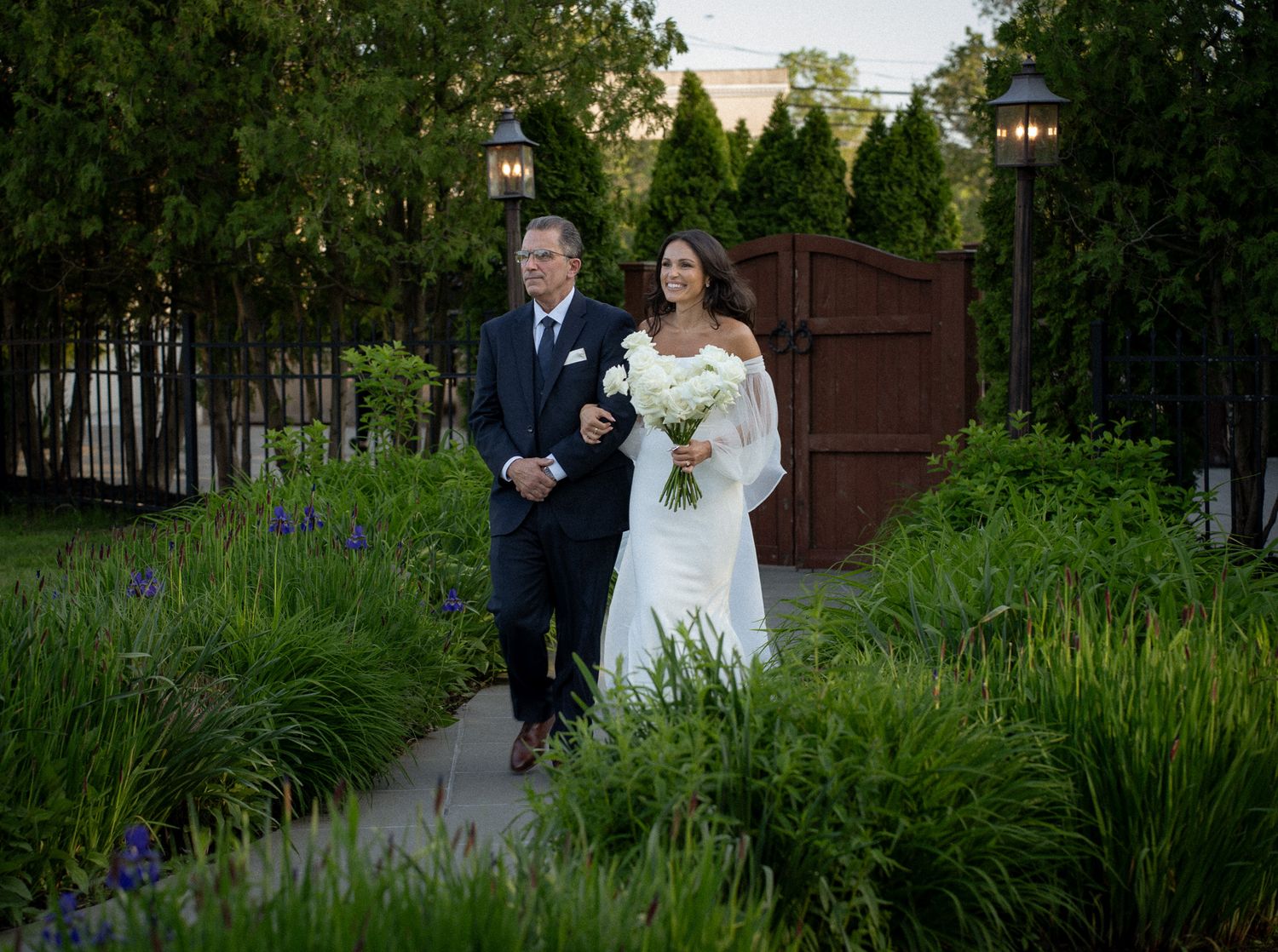 Bride walking down the Isle with her father at the Vineyards of Aquebogue, surrounded by lush greenery.
