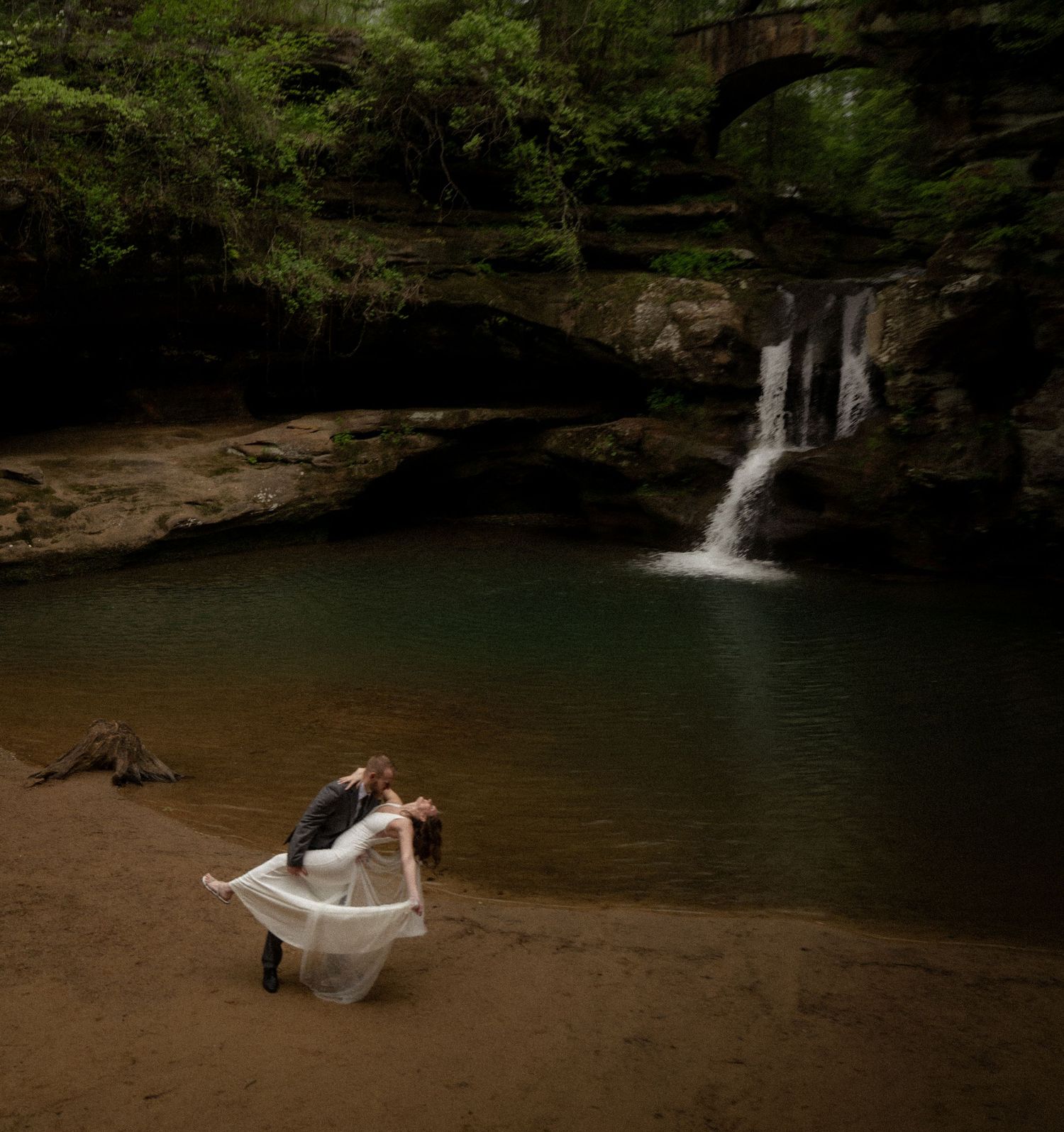 Bride and groom dancing barefoot by a secluded waterfall near NY, the bride’s veil twirling mid-air.