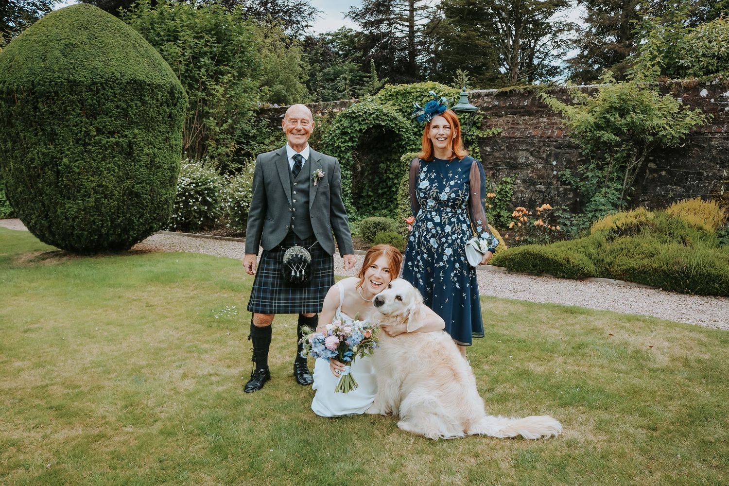 People gather at a beautiful garden venue for a wedding celebration with lush greenery and decorative landscaping.