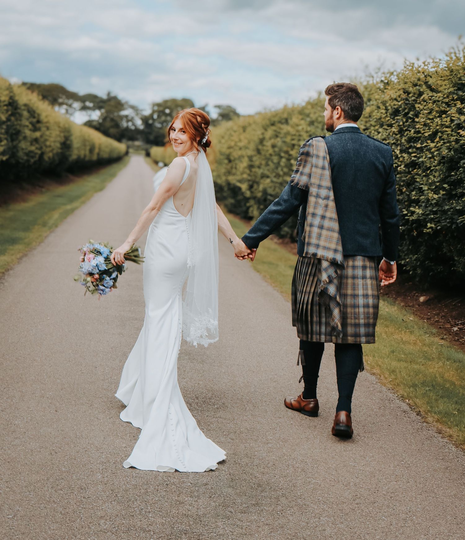 A wedding scene on a country path shows a couple in Scottish formal attire including a kilt and flowing white gown.