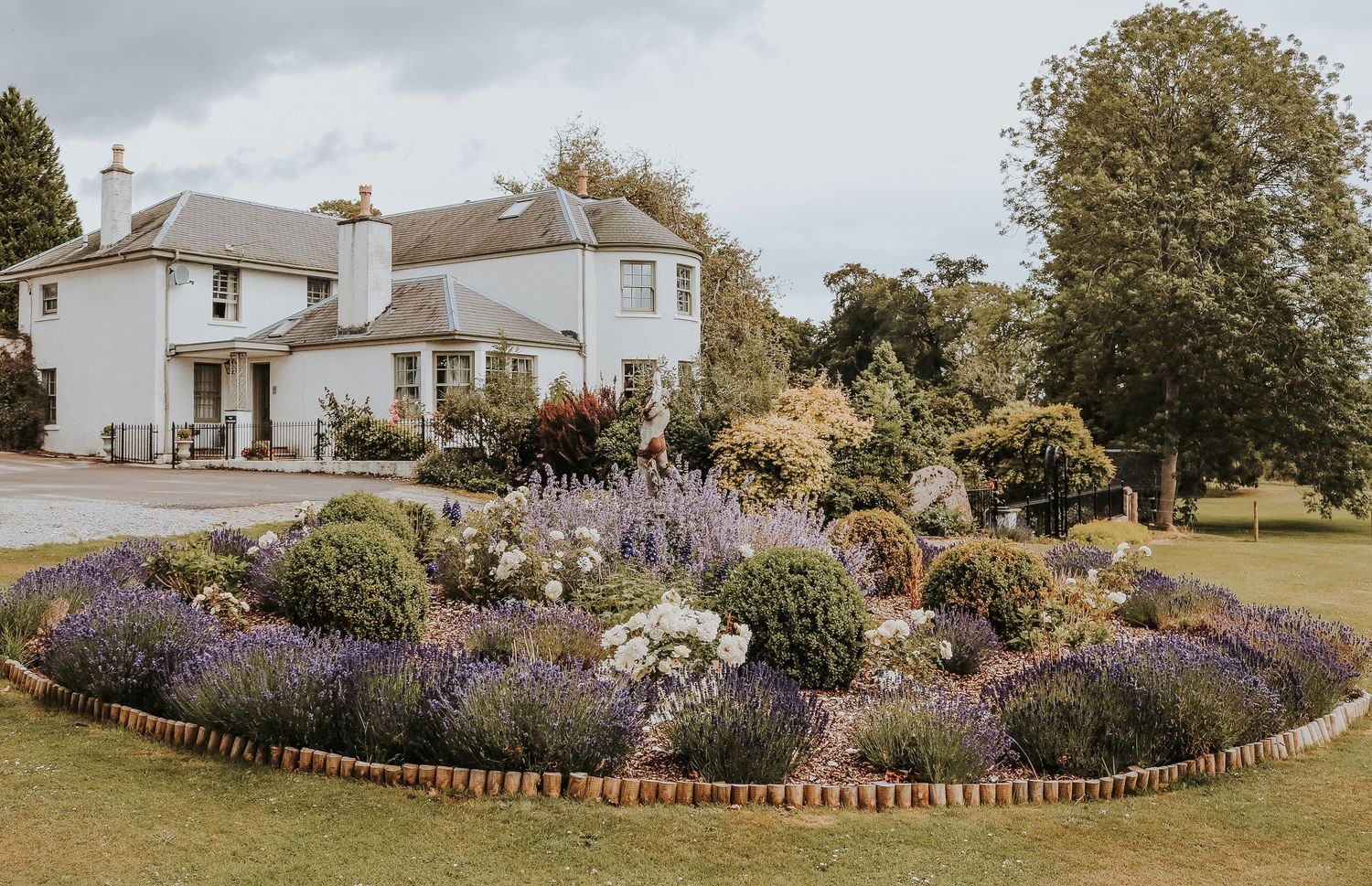 A panoramic series of garden landscapes with colorful flower beds and white houses along the property perimeter.