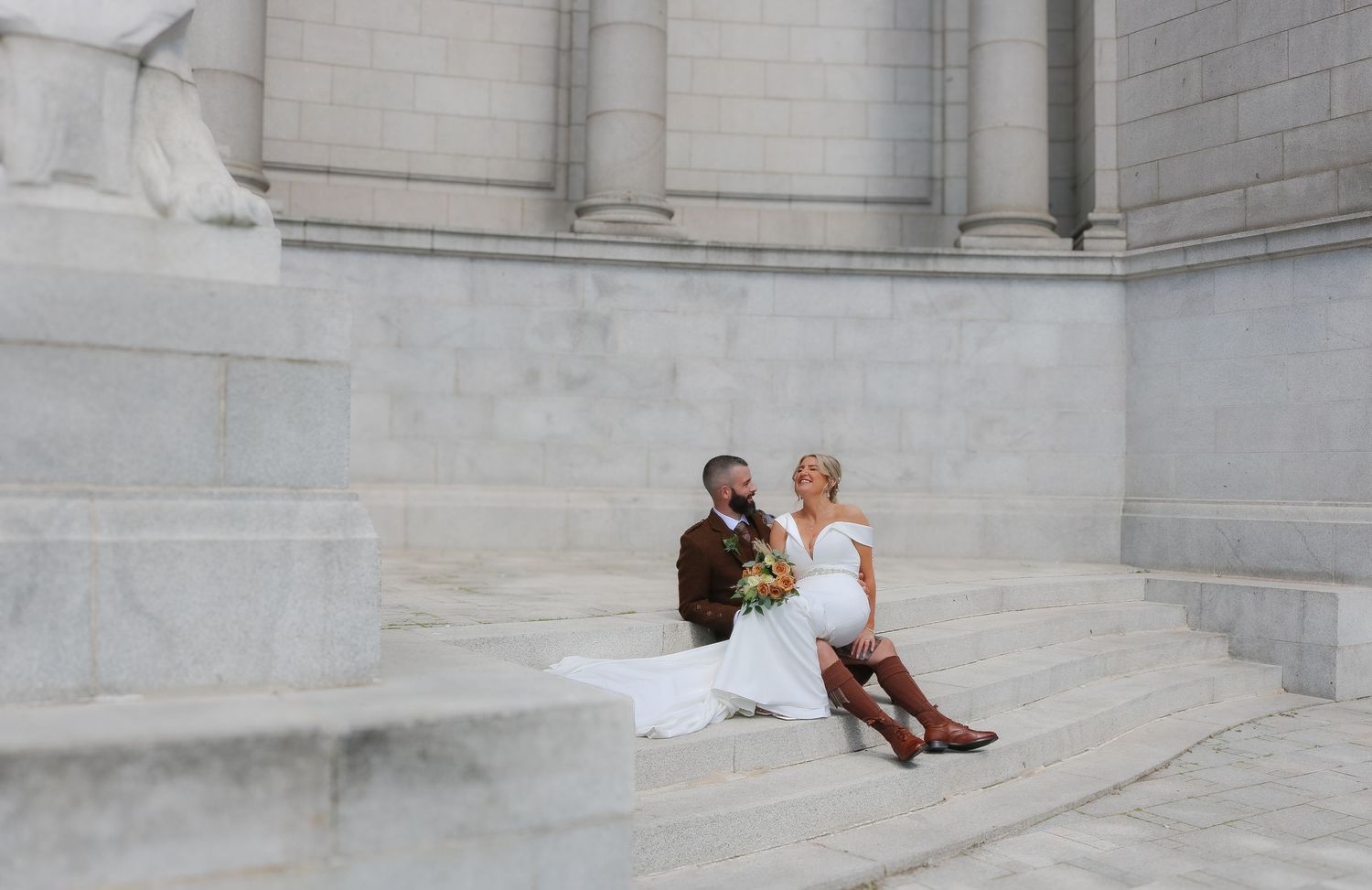 People lounge and relax on the grand marble steps of a historic government building on a sunny day.