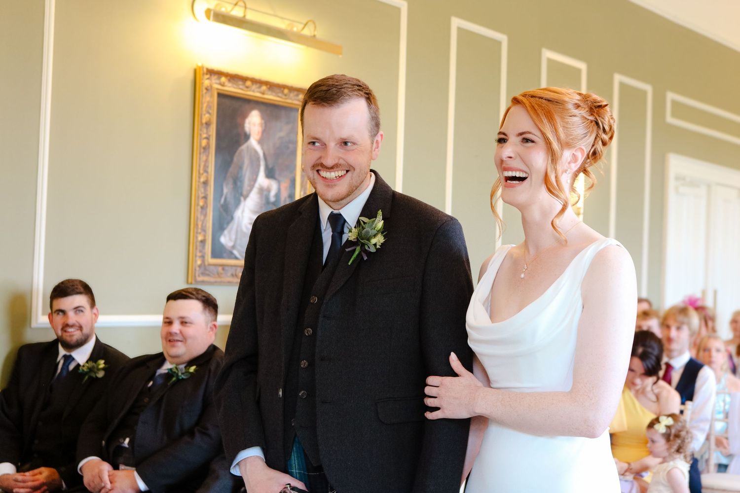 People gather indoors celebrating and socializing at what appears to be a wedding reception event.
