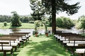 Row of wooden benches arranged on a green lawn for an outdoor wedding ceremony beside a tranquil pond.