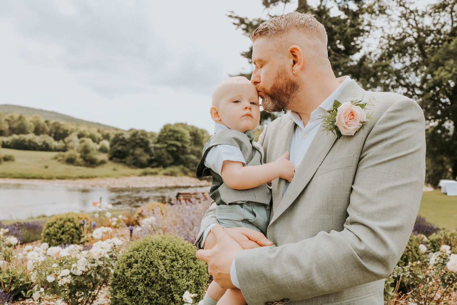 Father and young child sharing tender moments together in a lush outdoor garden setting during a family photoshoot.