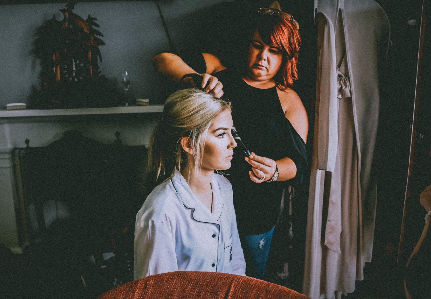 A stylist in black attire works on platinum blonde hair in a dimly lit salon setting.